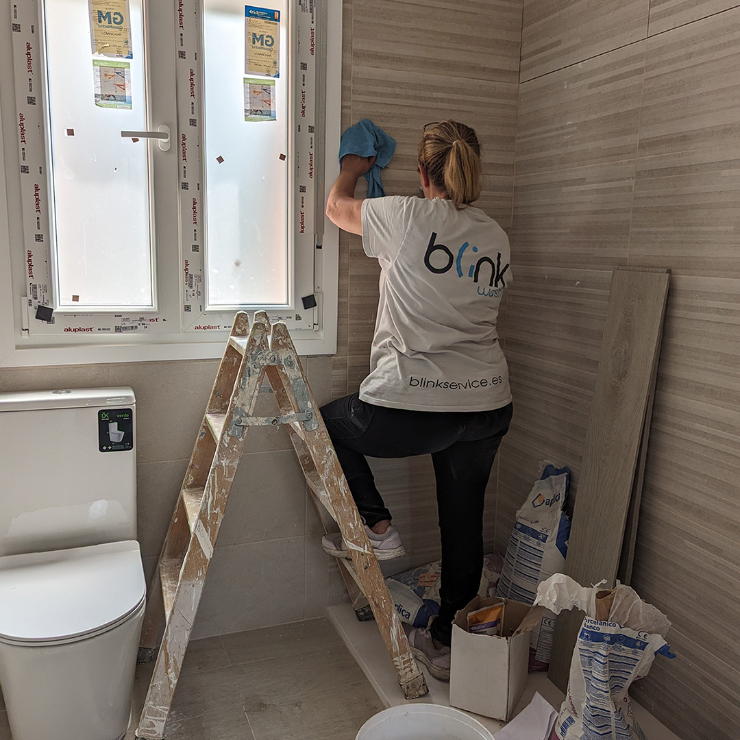 Profesional de Blink limpiando ventanas y azulejos tras reforma de baño
